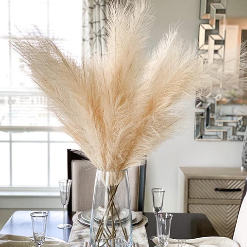 Pampas grass arranged in a tall glass vase in a living room
