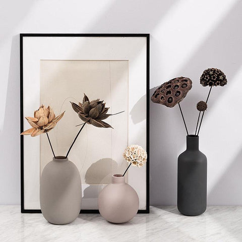Neutral Scandi ceramic vases with dried flowers beside a framed print