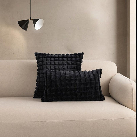 Raised square cushion covers in black, shown as a pair