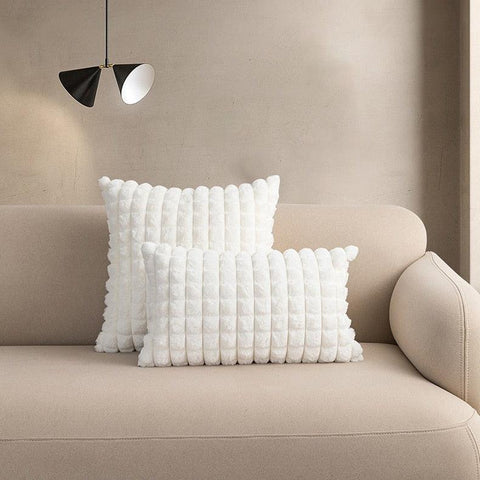 Raised square cushion covers in white, shown as a pair