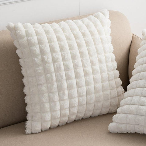 Raised square cushion covers in white on a linen sofa