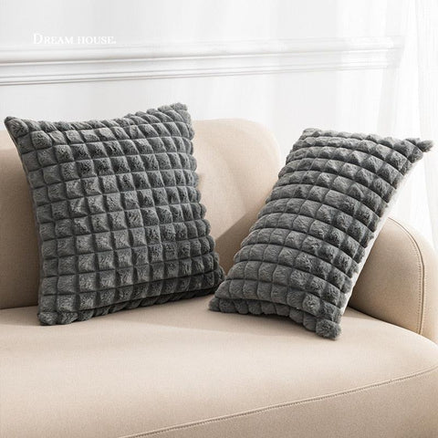 Raised square cushion covers in grey on a sofa