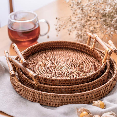 Nested rattan storage trays with wooden handles, styled with tea and dried grasses