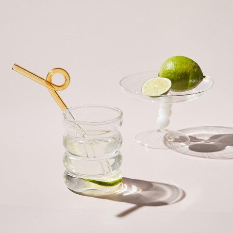 Clear retro ribbed glass tumbler with lime on a pale surface