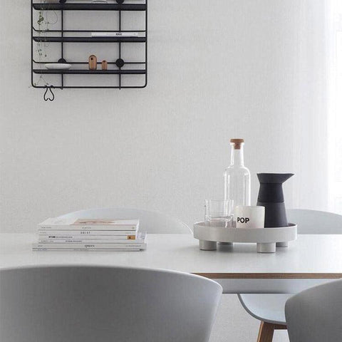Round footed storage tray in grey on a dining table