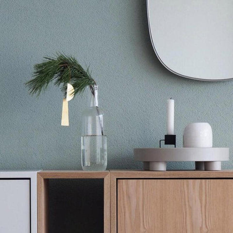 Round footed storage tray on a sideboard in a green-walled room