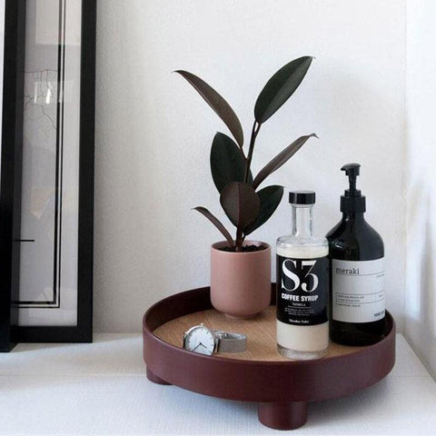 Round footed storage tray holding a plant and bathroom bottles