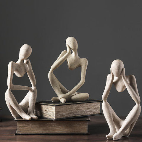 Three stone-finish Thinker sculptures grouped on stacked books