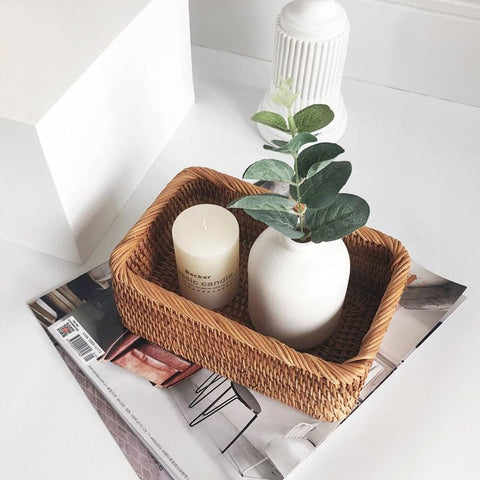 Rattan tray holding a potted plant and candles