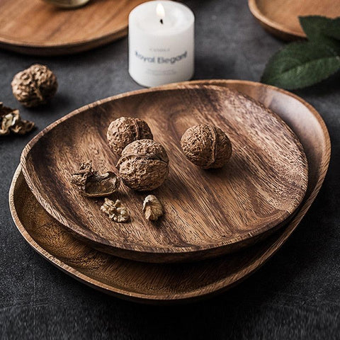 Stacked round wooden serving plates with a candle